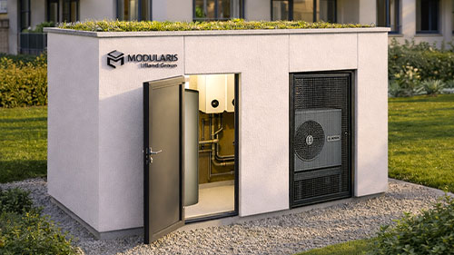 Modularis Energiezentrale mit heller Putzfassade, Gründach und integrierter Wärmepumpe vor einem Mehrfamilienhaus